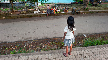 Ein kleines Mädchen beobachtet eine Gruppe Kinder, die am Straßenrand Früchte und Gemüse in Timor-Leste verkaufen. ©Plan International/Rob Few