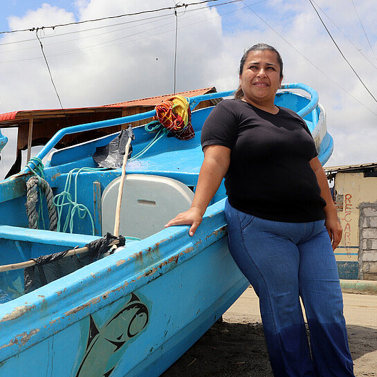 Eine Frau steht an ein Boot gelehnt, das am Strand steht
