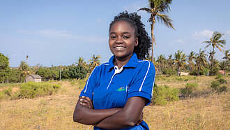 Eine junge Frau lächelt selbstbewusst in einem blauen Fußballtrikot 