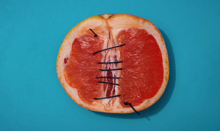 Zusammengenähte Grapefruit vor blauem Hintergrund.