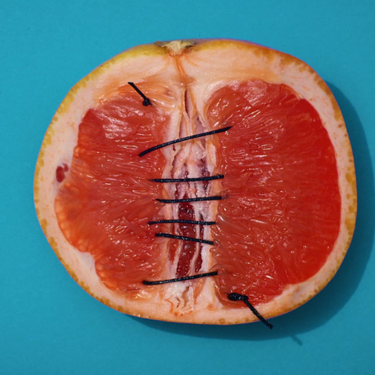 Zusammengenähte Grapefruit vor blauem Hintergrund.