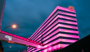 Das Bürogebäude der HELM AG ist im Dunkeln anlässlich des Weltmädchentages pink beleuchtet. 
