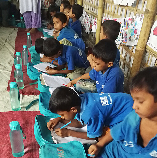 Neue Bildungschancen für Rohingya-Kinder Jungen zeichnen auf dem Boden