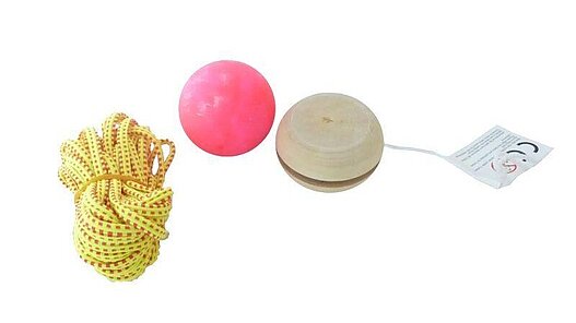 Zusammengelegtes gelbes Gummitwist, pinkfarbener Flummi und Jojo aus Holz.