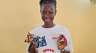 Carla steht bei einer Veranstaltung zum Menstruationsgesundheitstag und präsentiert Informationsmaterialien