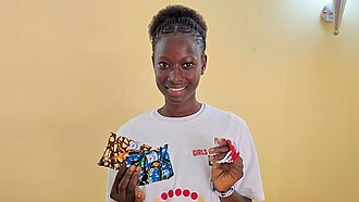 Carla steht bei einer Veranstaltung zum Menstruationsgesundheitstag und präsentiert Informationsmaterialien