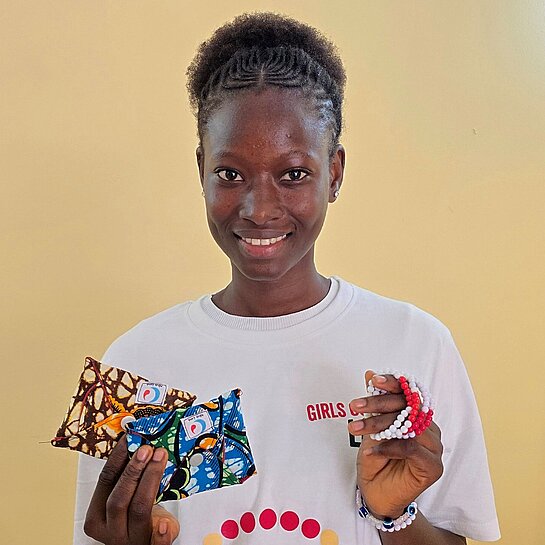 Carla steht bei einer Veranstaltung zum Menstruationsgesundheitstag und präsentiert Informationsmaterialien