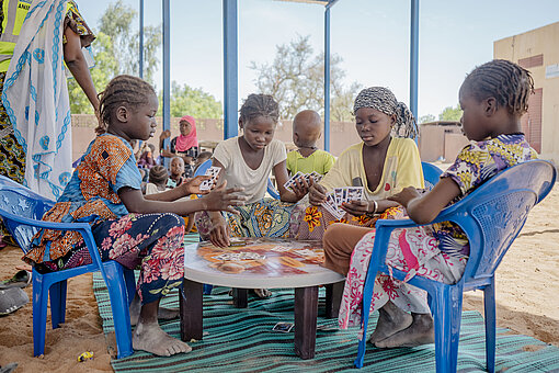 Vier Mädchen sitzen an einem Tisch und spielen Karten