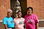 Drei junge Frauen aus Simbabwe halten sich in den Armen und lachen. Sie tragen T-Shirts mit der englischen Aufschrift "Mein Körper, meine Zukunft".