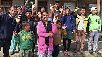Teachers Bidhaya (centre in pink) and Ramesh, (left in blue) make the sign for ‘happy’ with some of the students at the deaf school