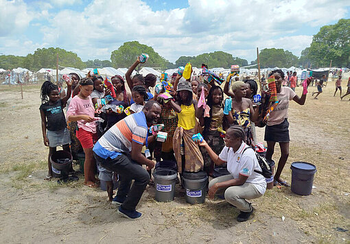 Eine Gruppe mosambikanische Frauen und Mädchen freuen sich über Menstruationshygiene-Kits