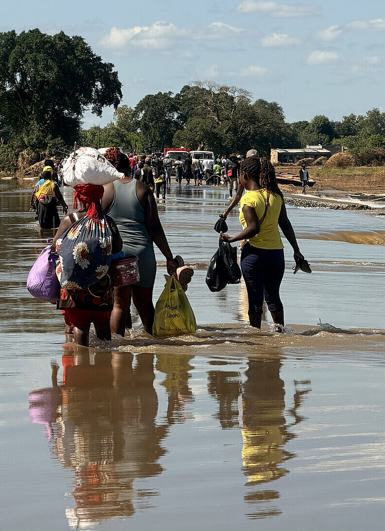 Mehrere Menschen waten durch Hochwasser in Mosambik