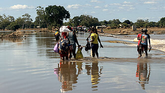 Mehrere Menschen waten durch Hochwasser in Mosambik