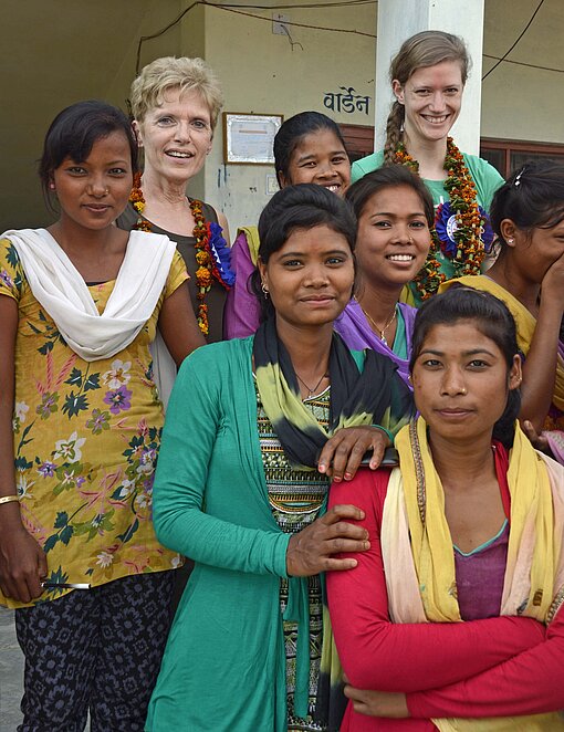 Besuch im Plan-Projekt in Nepal Nepalesinnen mit Saris stehen vor einem Haus in Nepal