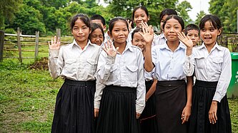 Schülerinnnen in Kambodscha winken in Kamera