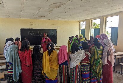 Frauen hören einer Frau zu, die vor einer Tafel steht