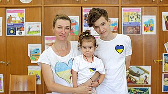 Eine Frau steht zusammen mit ihren beiden Kindern in einem Schutzzentrum für Gefüchtete in Bukarest, Rumänien