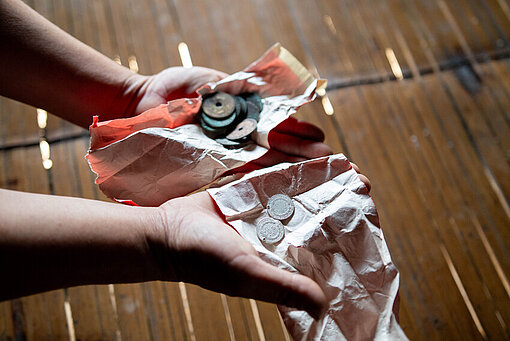 In zwei ausgebreiteten Händen liegen Silbermünzen auf einem Tuch