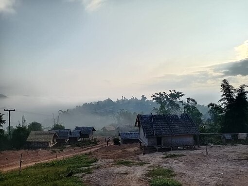 Foto von nebeligem Acker mit Haus in Laos.