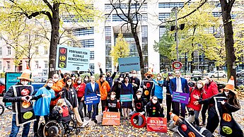 Eine Gruppe Aktivistinnen steht vor dem Bundestag. Sie tragen T-Shirts mit den Namen verschiedener NGOs.