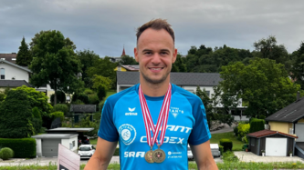 Porträt des Sportlers Sebastian Aschenbrenner mit Medaille.