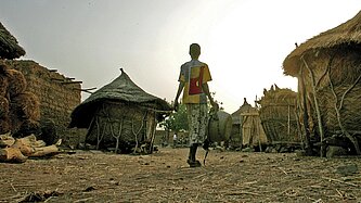 Ein Mädchen läuft über einen Dorfplatz