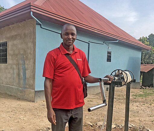 Ehemaliges Plan-Patenkind Tamba Michel Ein junger Mann steht an einem Brunnen in Guinea