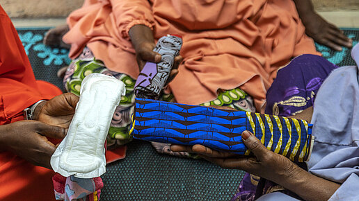 Drei Frauen zeigen ihre selbstgemachte und widerverwendbaren Binden.