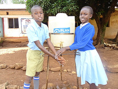 Zwei Kinder waschen sich die Hände an einer Wasserstation