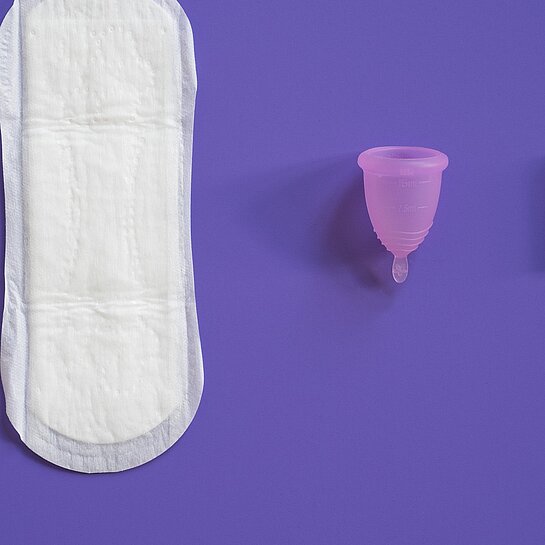 Eine Binde, eine Menstruationstasse und ein Tampon liegen lebeneinander