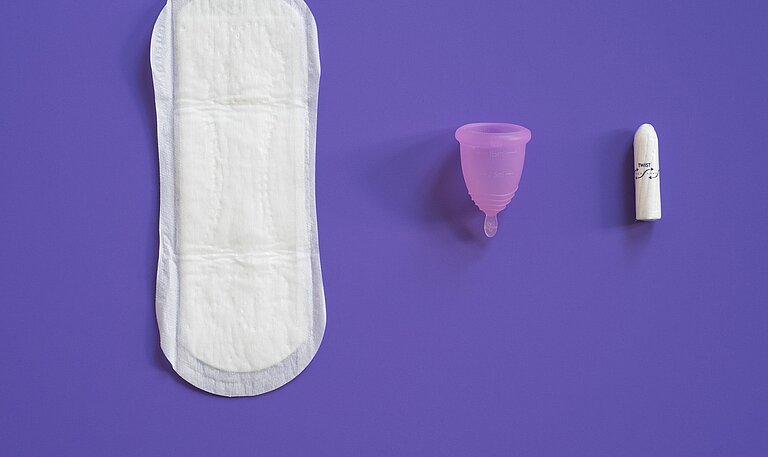 Eine Binde, eine Menstruationstasse und ein Tampon liegen lebeneinander