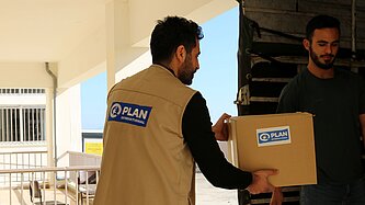 Plan Mitarbeiter bringt ein Paket mit Schulutensilien in den Südlibanon