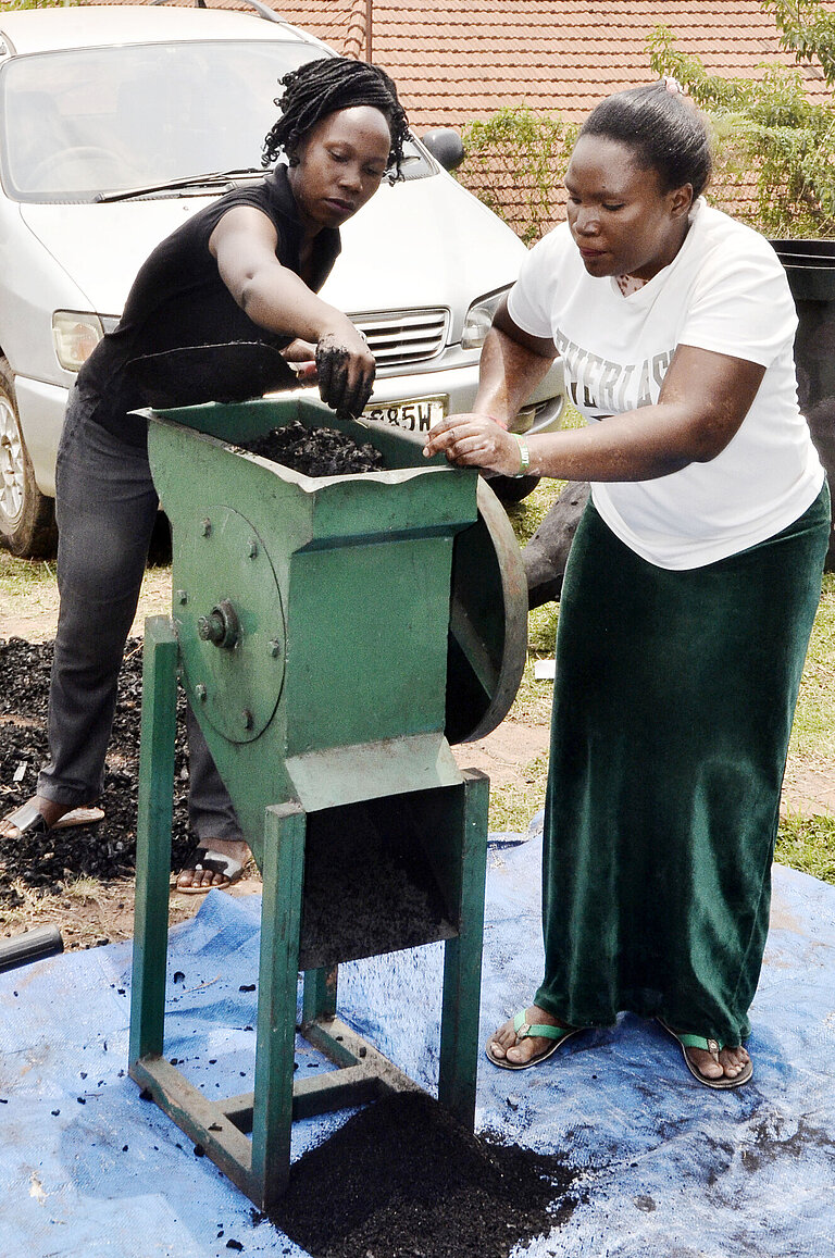 Zwei Frauen werfen Rohmaterial in eine Maschine