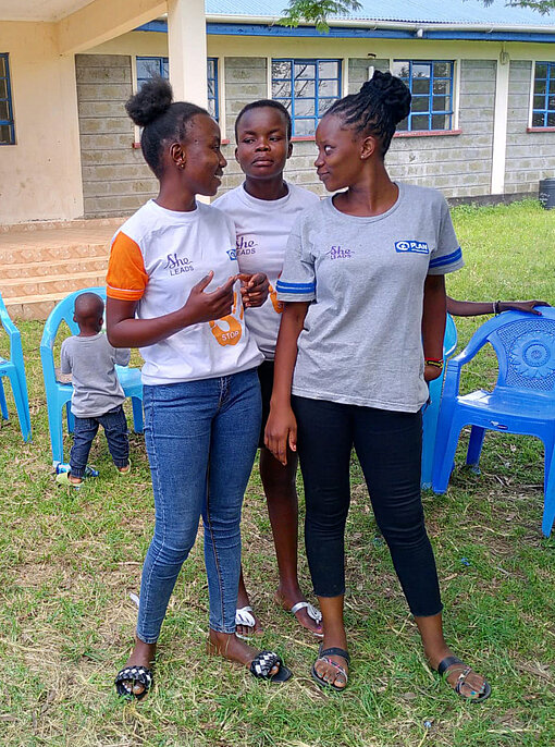 Drei junge Frauen stehen zusammen und schauen sich an