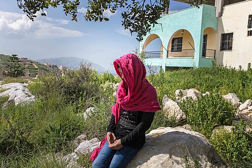 Gleiche Rechte für alle? Amal sollte als Elfjährige in Libanon verheiratet werden Ein verschleiertes Mädchen sitzt auf einer Mauer vor einem Haus