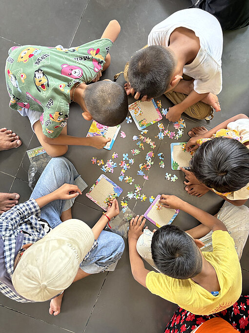 Mädchen und Jungen sitzen auf dem Fußboden zusammen und spielen
