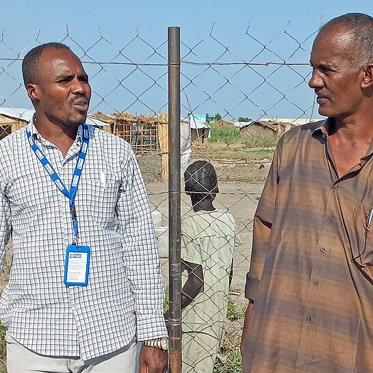 Zwei Männer unterhalten sich an einem Brunnen