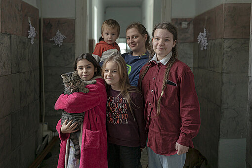 Eine Frau und vier Kinder stehen für ein Gruppenbild beisammen. Eins der Mädchen hält eine Katze auf dem Arm.