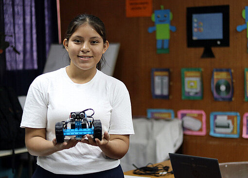 Mädchen hält ihren selbstgebauten kleinen Roboter in den Händen