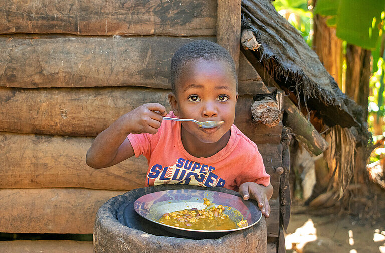 Ein kleiner Junge nimmt einen Löffel voll Suppe
