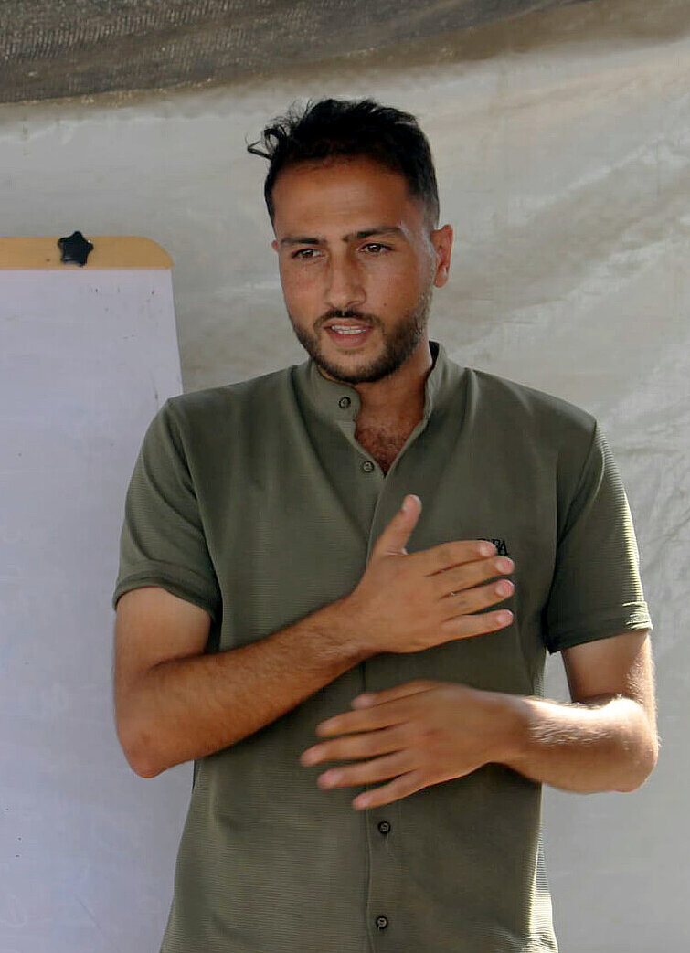 Mohammed steht vor einem Flipboard und spricht zu einer Gruppe Menschen