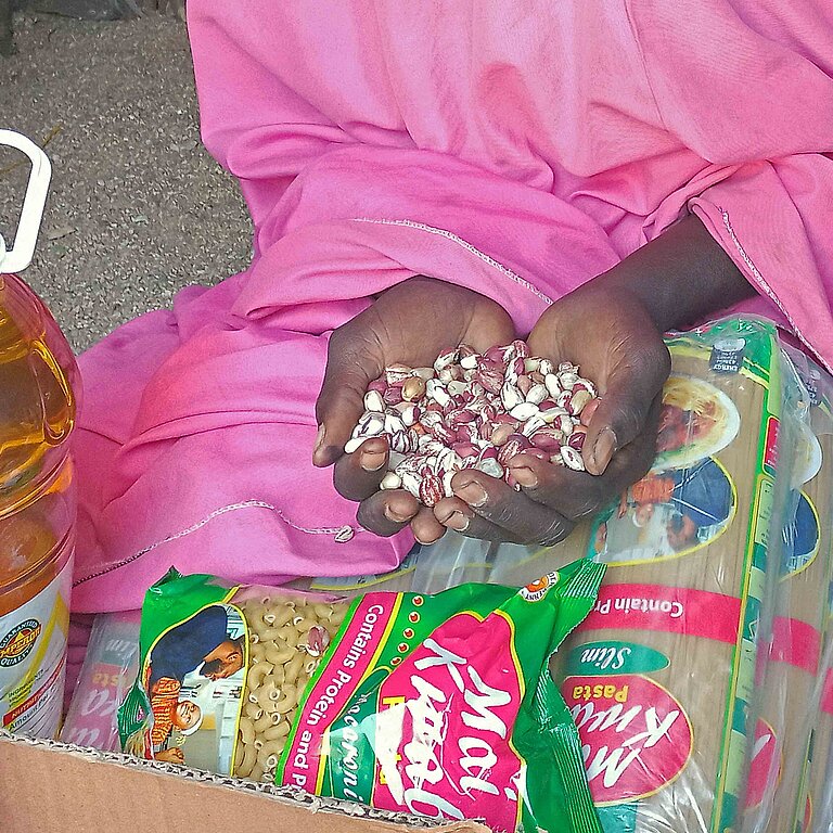 Die Hände einer Frau in rosa Kleid halten eine Handvoll Erdnüsse