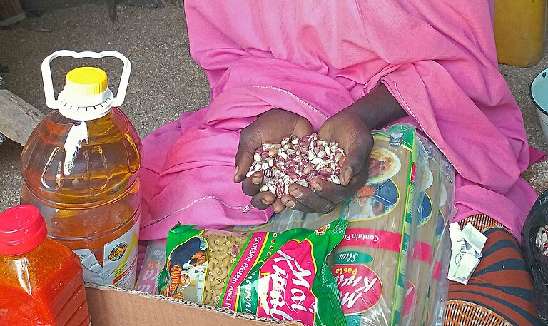 Die Hände einer Frau in rosa Kleid halten eine Handvoll Erdnüsse