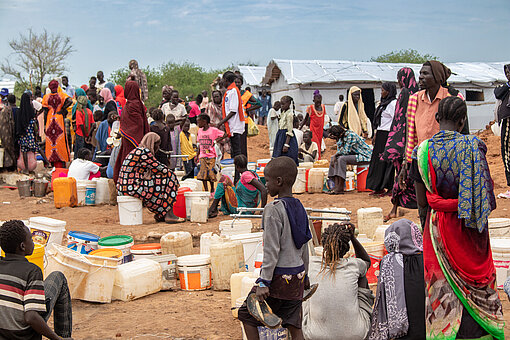 In einem Camp für geflüchtete Menschen in Südsudan stehen viele Menschen mit Kanistern für Wasser an