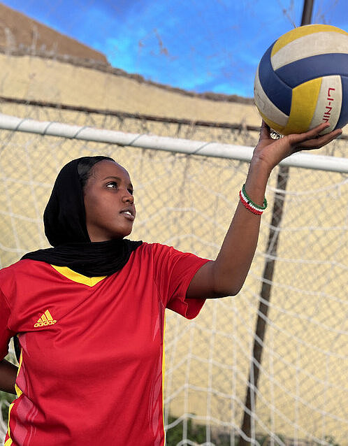 Zhahruzaad hält einen Fußball in die Luft Eine junge Frau hält einen Fußball neben sich in die Luft