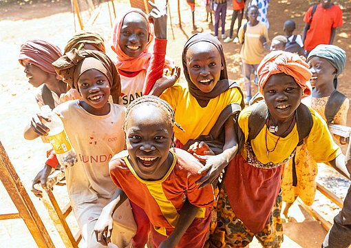 Eine Gruppe Mädchen in bunten Kleidern schaut lachend in die Kamera