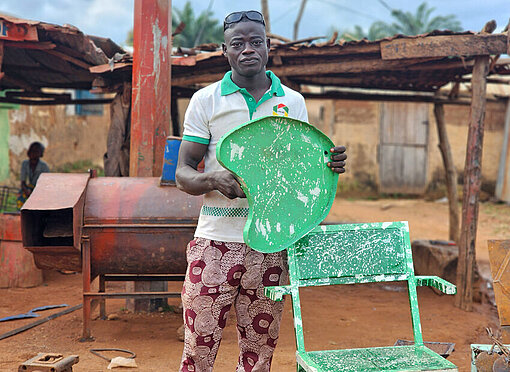 Ein Mann hat Gartenmöbel aus Metall geschweißt, die er vorzeugt