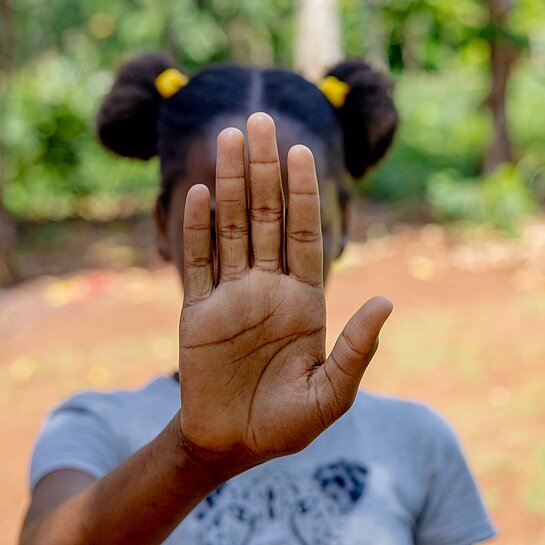 Mädchen hält Hand vor Gesicht 