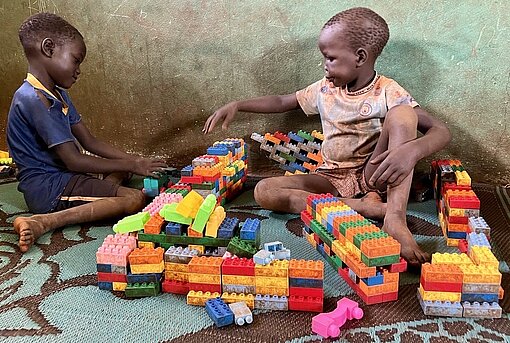 Zwei Jungen sitzen zwischen Duplo-Steinen und bauen einen Turm