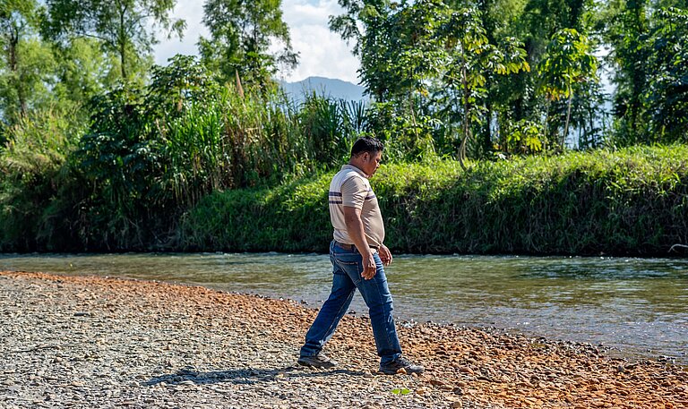 Aníbal steht am Fluss neben seines Hauses 